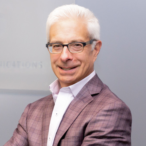 Tony DeFazio smiles at the camera wearing glasses and a gray suit jacket