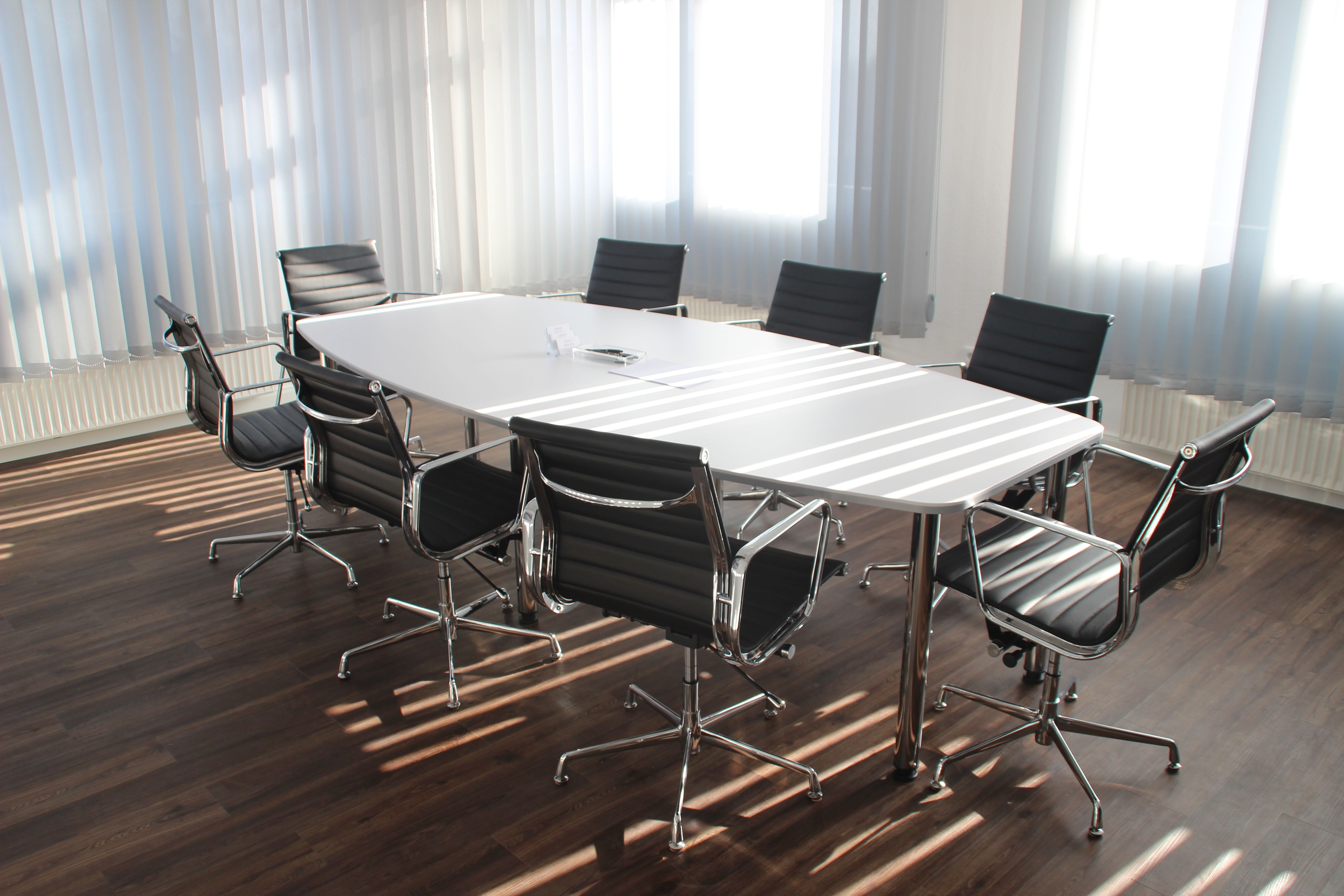 An empty white conference table sits in a room during late afternoon